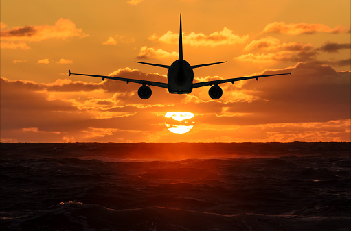 Airplane in the sky is flying into the sunset over the sea 3D rendering