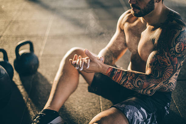 Don't wish for it, work for it. Young athlete resting in gym after hard cross training. Wearing professional sport clothing . crossfit chalk weightlifting weight training stock pictures, royalty-free photos & images
