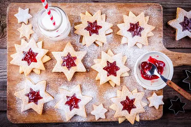 Christmas Linzer cookies with raspberry jam on a rustic wooden background
