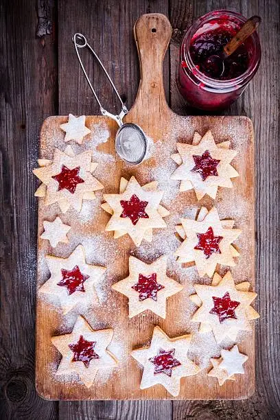 Christmas Linzer cookies with raspberry jam on a rustic wooden background