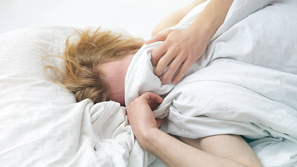 istock red-haired young man lying in bed covering up his face 628895730