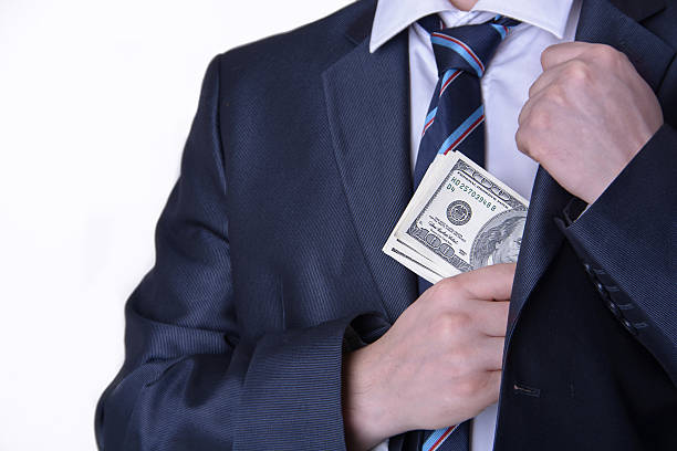 Businessman putting money in suit jacket pocket Businessman putting money in suit jacket pocket leather pocket clothing hide stock pictures, royalty-free photos & images