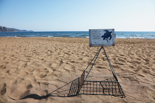 Mugla, Turkey - June 20, 2016: Nest cage proctection sign of the sea turtle eggs on the Iztuzu Beach, a breeding ground for the endangered loggerhead sea turtle (caretta caretta) species. Iztuzu Beach is a 4.5 km long beach near Dalyan and one of the prime nesting habitats of the loggerhead turtle in the Mediterranean.'