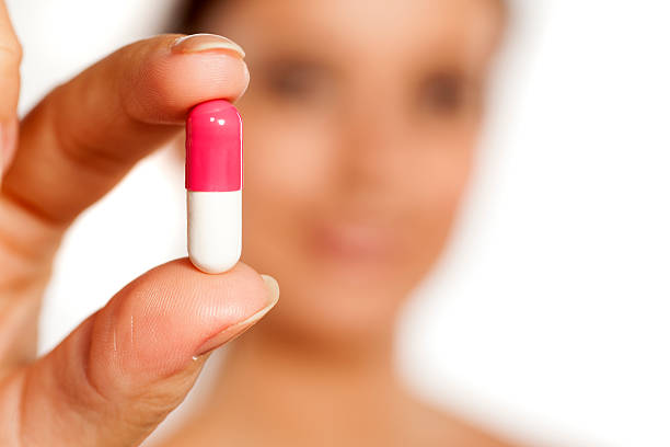 istock Young woman holds a capsule in her fingers 628900816