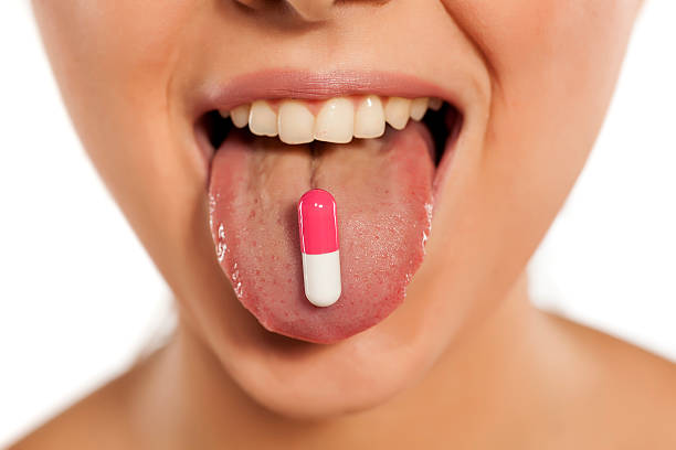 istock Young holds a capsule on her tongue 628900852
