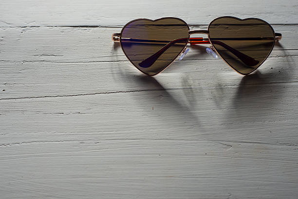 istock Heart shaped rainbow sunglasses on wood texture 628908882