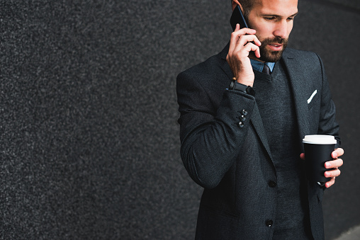 Happy young businessman talking on a cellphone outdoors.