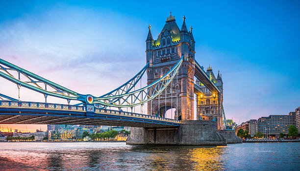 london tower bridge illuminated at sunset over river thames panorama - tower bridge stockfoto's en -beelden