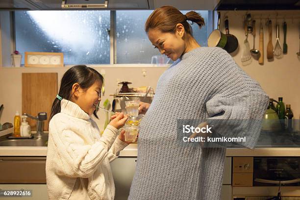Pregnant Mother Making Drink With Her Daughter In Her Kitchen Stock Photo - Download Image Now