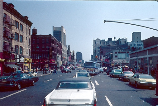 New York City, NYS, USA, April 28, 1976. District of Harlem. Lively streets scene on the Dr. Martin Luther King Jr. Blvd. crossing Frederick Douglass Blvd.