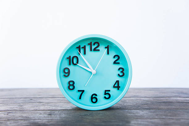 istock Green clock on a wooden table on a white background. 628932740