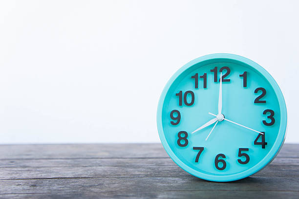 istock Green clock on a wooden table on a white background. 628932758