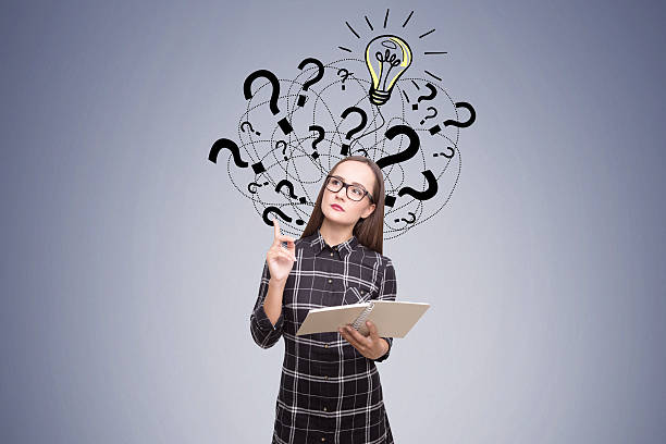 istock Nerdy woman near dark gray wall with question marks 628934422