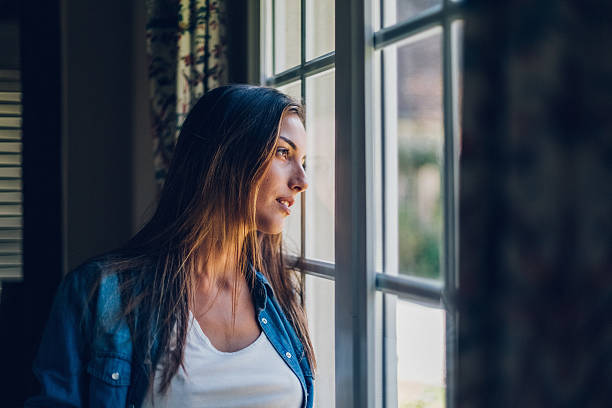 istock Dreamy woman looking through the window 628935334