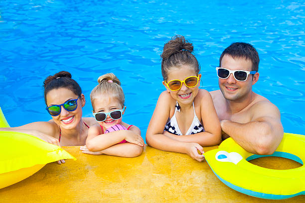famille heureuse avec deux enfants qui s’amusent dans la piscine - être aux anges photos et images de collection