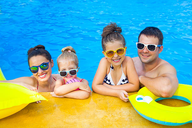 família feliz com duas crianças se divertindo na piscina - tropical climate family relaxation men - fotografias e filmes do acervo