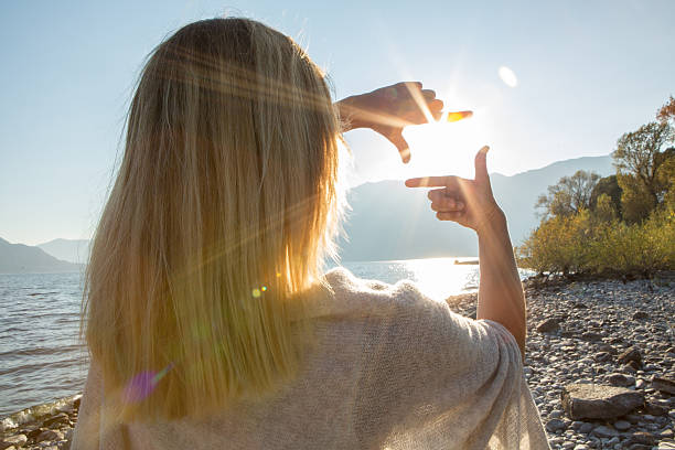 istock Woman's hands frame sunrise over mountain lake 628941780