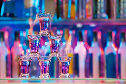 Picture of pyramid line of burning alcohol cocktails standing on a bar counter with copy-space