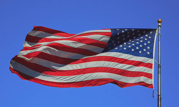 istock USA flag flying in strong wind in a clear sky 628952066