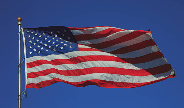 istock US flag flying in strong wind in a blue sky 628963106