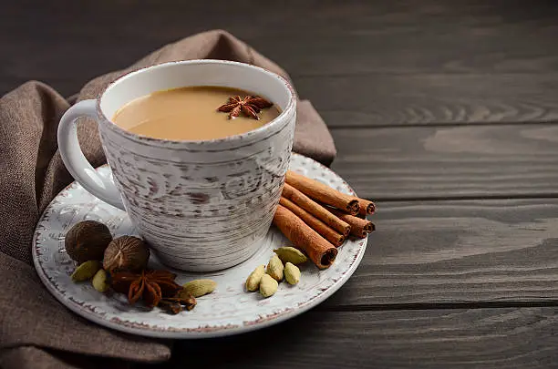 Indian masala chai tea. Spiced tea with milk on dark wooden background. Selective focus, horizontal, copy space.