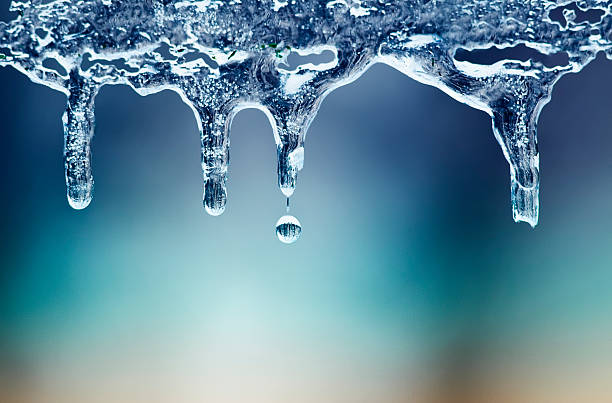 光沢のある澄んだ氷のつららは晴れた日に掛かる - melting ストックフォトと画像