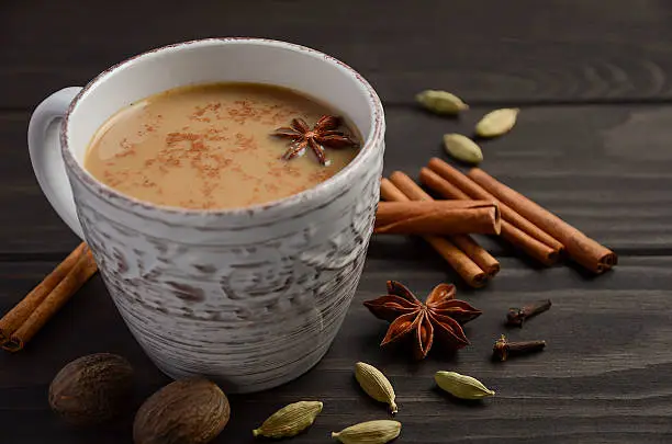 Indian masala chai tea. Spiced tea with milk on dark wooden background. Selective focus, horizontal.