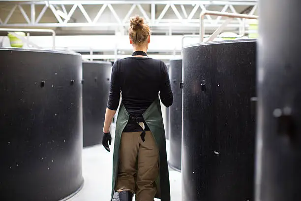 Rear view shot of female worker walking through storage tanks in fish farm