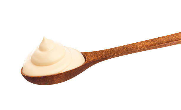 istock Sour cream in wooden spoon isolated on white background 628967140