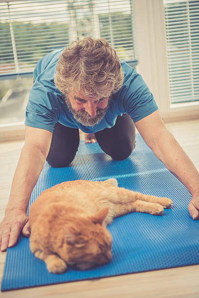 istock Senior Man exercising at Home with his Ginger Cat 628976016