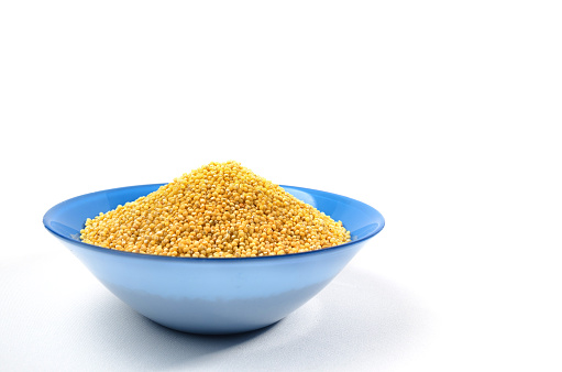 Blue bowl of barley grits isolated on white. On left side