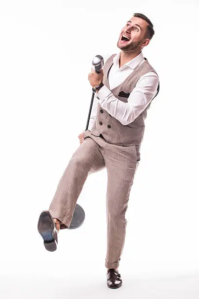 Young showman in suit dance and singing with emotions gesture over the microphone with energy. Isolated on white background. Singer concept.