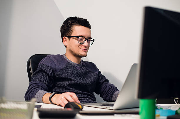 istock Busy working. Pensive young handsome man wearing glasses on laptop 628984146