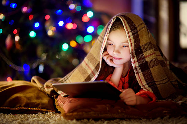 istock Adorable little girl using tablet by fireplace on Christmas evening 628984412