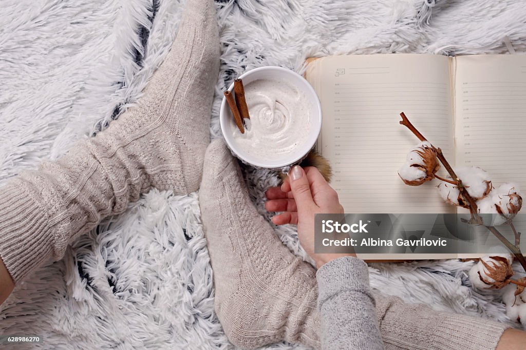 Donna che indossa accoglienti calzini di lana calda, leggendo un libro - Foto stock royalty-free di Accogliente