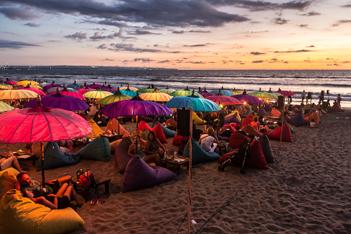 Kuta, Indonesia - February 19, 2016: A large crowd of tourists enjoy the sunset at a beach bar on Kuta beach in Seminyak, Bali. The island is famous for its nightlife.