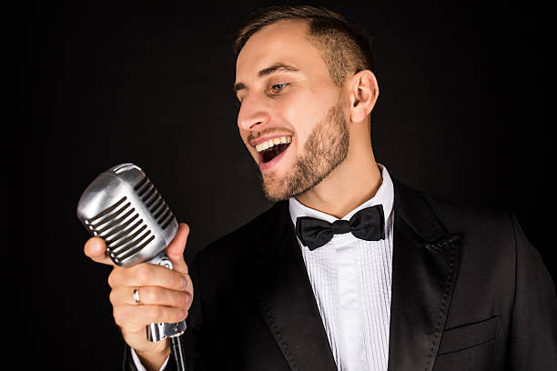 istock Portrait of handsome man sing on microphone on black background 628994494