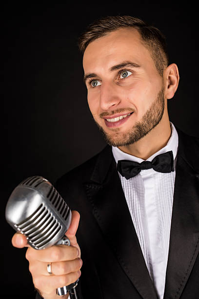 istock Portrait of handsome man sing on microphone on black background. 628994590