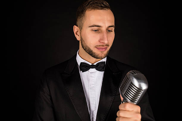 istock Portrait of handsome man sing on microphone on black background. 628994748