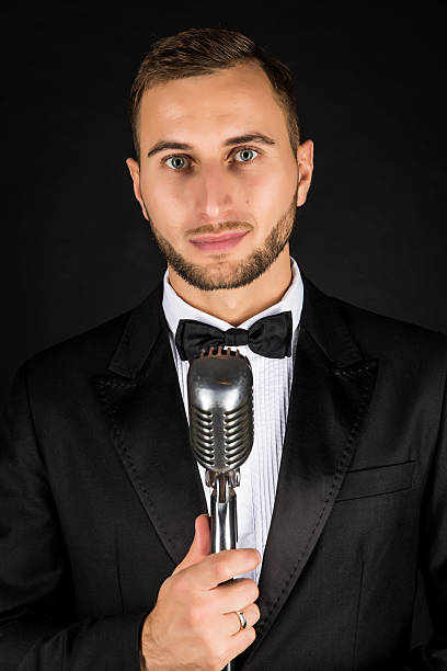 istock Portrait of handsome man sing on microphone on black background. 628994898
