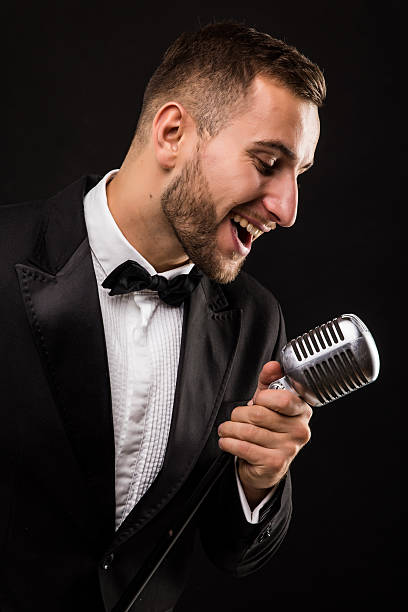 istock Portrait of handsome man sing on microphone on black background. 628995066