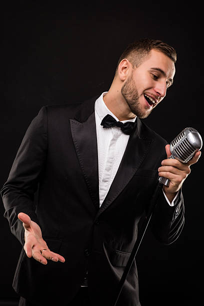 istock Portrait of handsome man sing on microphone on black background. 628995124