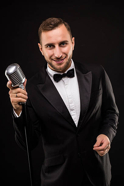 istock Portrait of handsome man sing on microphone on black background. 628995190