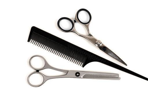 Professional haircutting scissors and comb isolated on white background