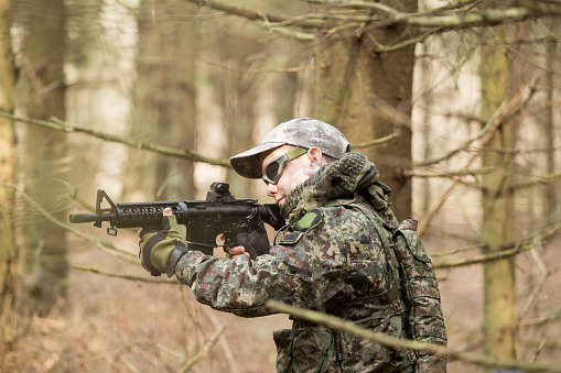 soldiers in the coniferous forest with a gun, aiming ready for battle