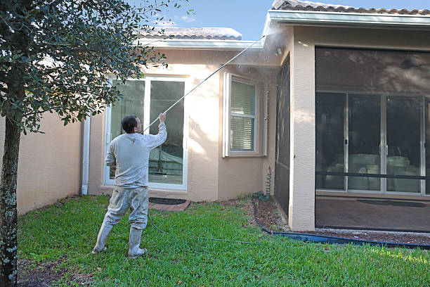 Series:Hispanic worker power washing back of one story home stock photo