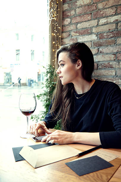 Young woman working in a restaurant with red wine.