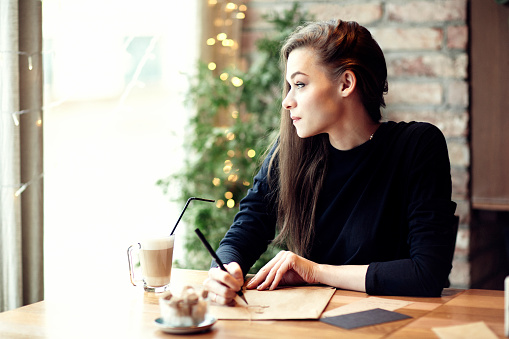 Young caucasian woman working, writing in a restaurant. Business concept. Stationary layouts