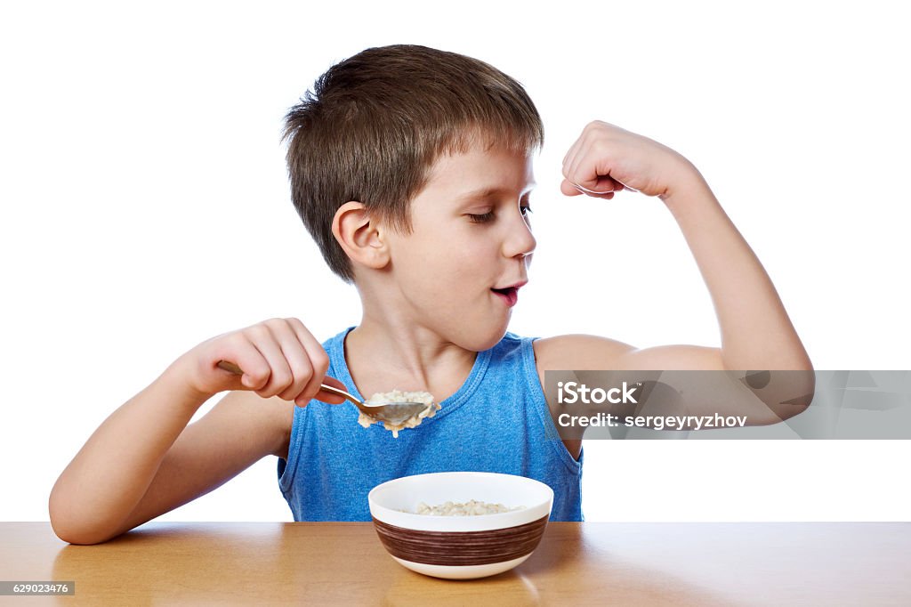 Happy boy eating porridge at table isolated Happy boy eating porridge at the table isolated white Child Stock Photo