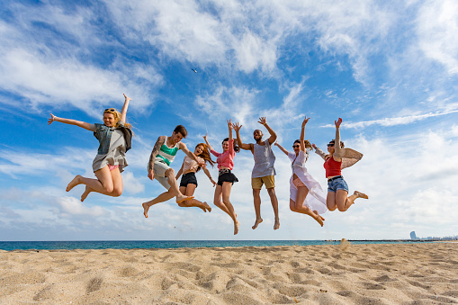 Celebrating group of friends jumping at the beach in Barcelona Spain